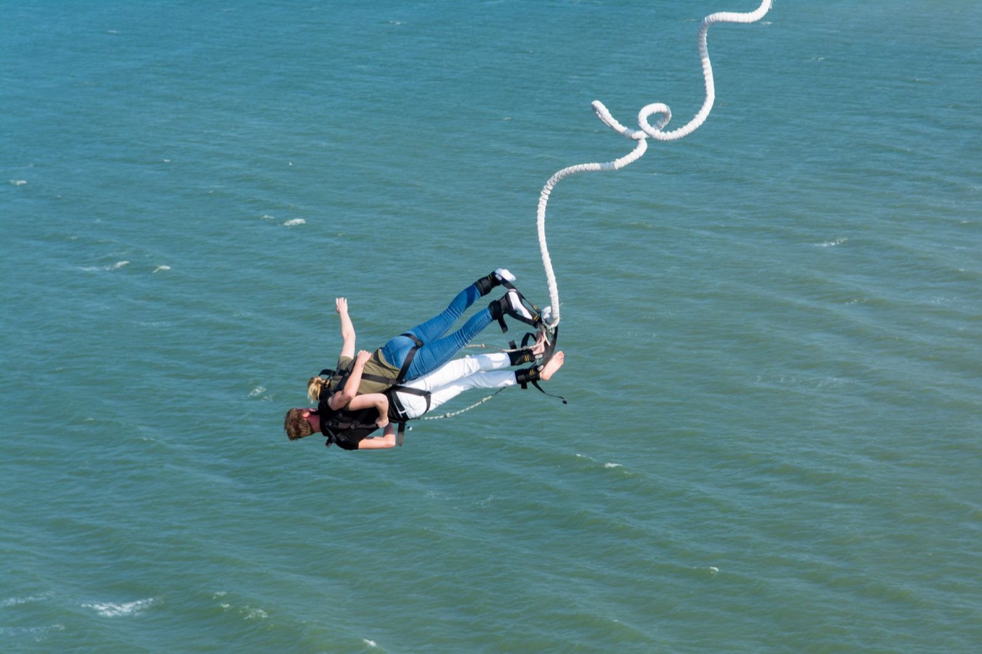 Two people bungee jumping together on one cord high above the water