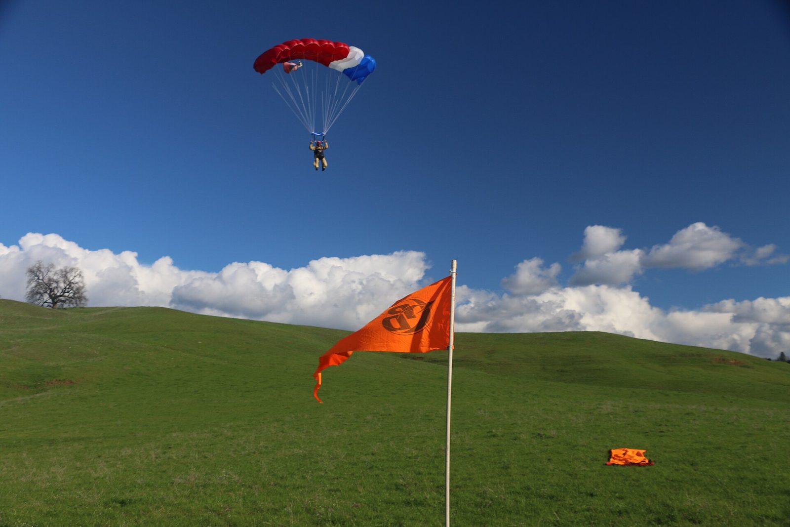 Skydiver coming in to land under canopy on a grass field